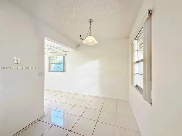 a view of an empty room with window and chandelier fan