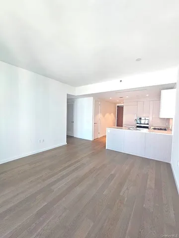 a view of a kitchen with kitchen island wooden floors and stainless steel appliances