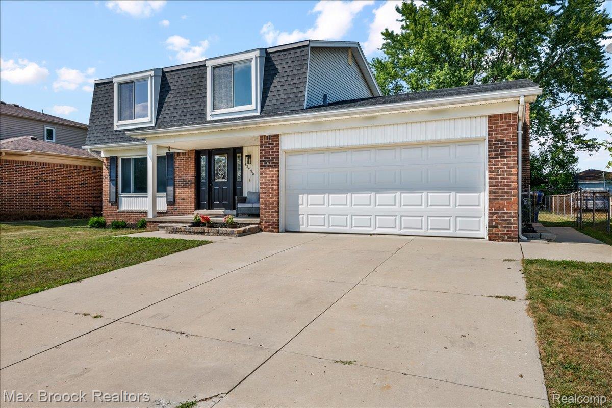 42470 Bishop Road Canton, MI 48188 - Photo 2 of 37 Brick exterior with a gambrel roof and dormer windows, featuring a two-car garage and a concrete driveway
