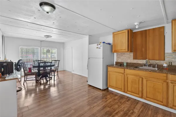 a kitchen with stainless steel appliances granite countertop a refrigerator a sink dishwasher a dining table and chairs with wooden floor