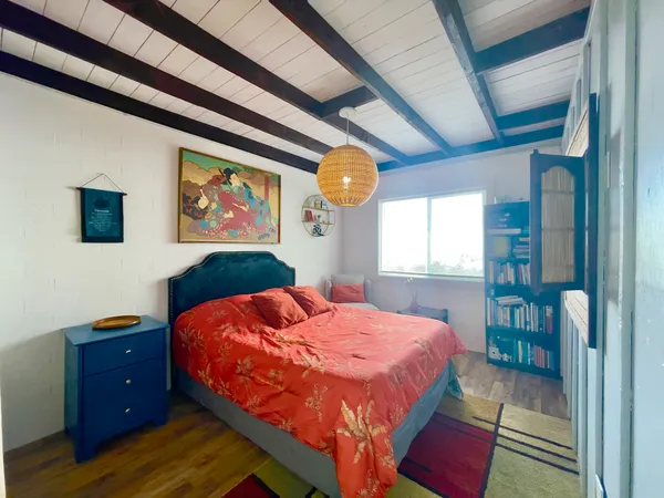 a bedroom with a bed and a dresser next to a window