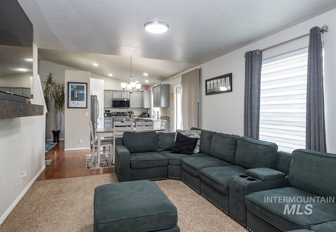 805 Bison Way Caldwell, ID 83607 - Photo 20 of 45 Open-concept living space featuring vaulted ceilings, recessed lighting, and a kitchen with grey cabinetry and stainless steel appliances