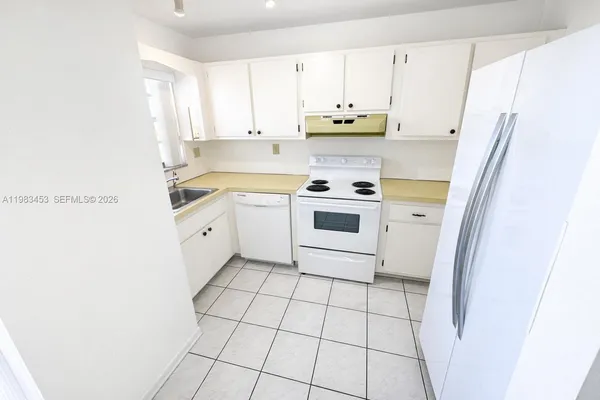 a kitchen with stainless steel appliances a white refrigerator a sink a stove a microwave and cabinets