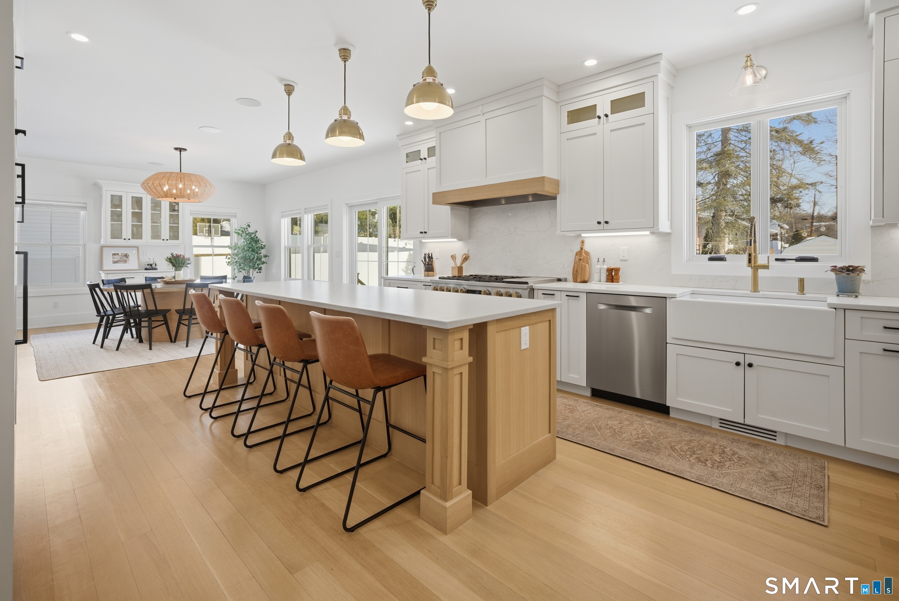 196 Robin Lane Fairfield, CT 06824 - Photo 19 of 37 a kitchen with stainless steel appliances kitchen island granite countertop a stove a sink a dining table and chairs with wooden floor