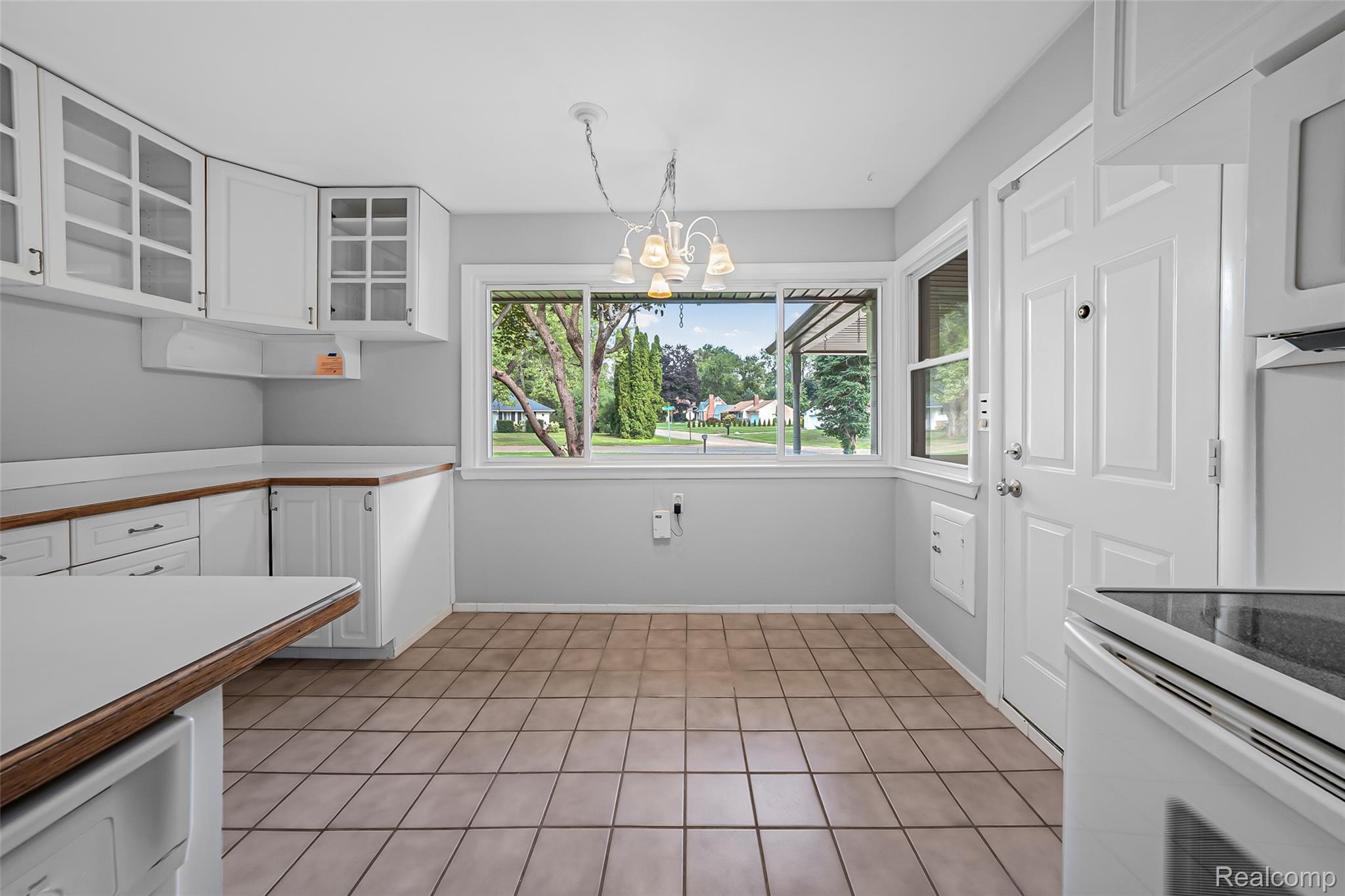 2329 Rutherford Road Bloomfield Hills, MI 48302 - Photo 35 of 46 White cabinetry with glass-front uppers, wood-finish countertops, tile flooring, and a large window