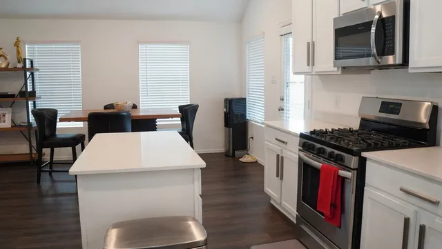 a kitchen with stainless steel appliances granite countertop a stove top oven a sink a dining table and chairs