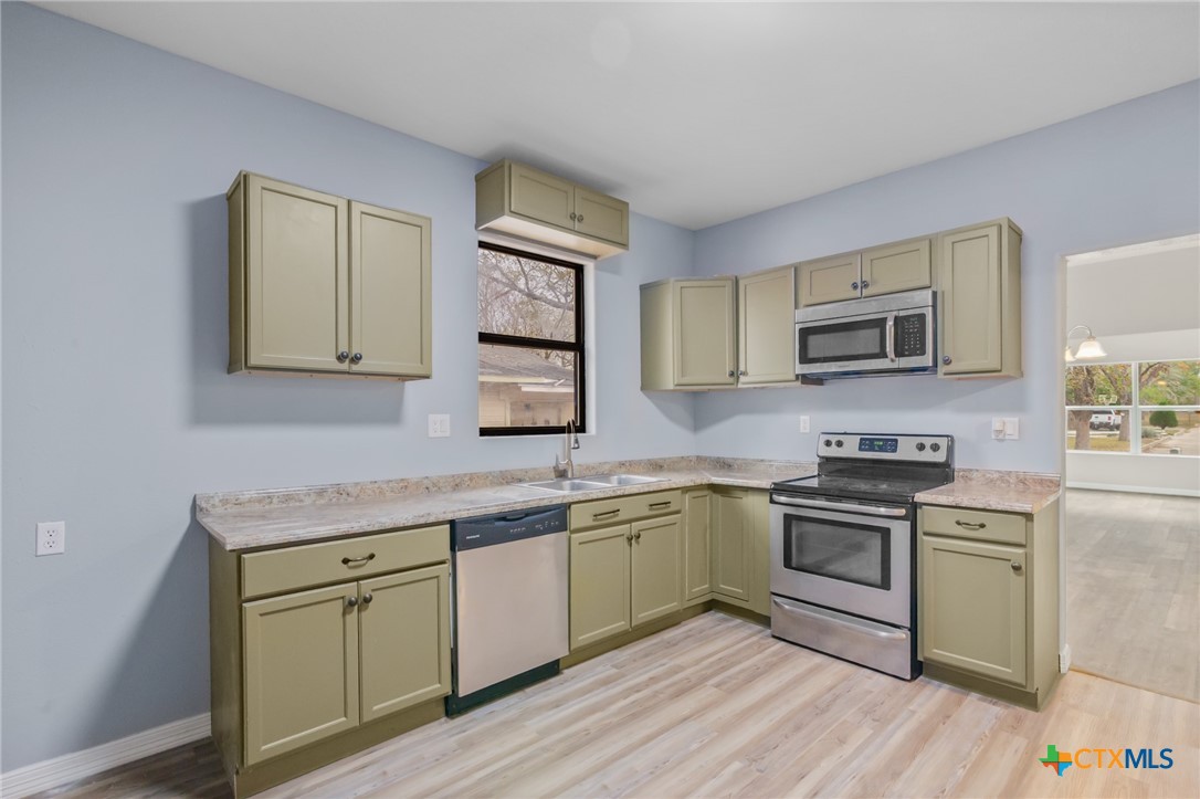 406 Hubbard Street Yoakum, TX 77995 - Photo 16 of 37 a kitchen with stainless steel appliances granite countertop a sink a stove top oven and wooden floors