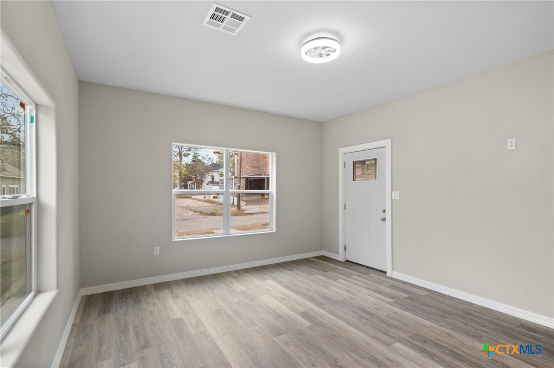 406 Hubbard Street Yoakum, TX 77995 - Photo 6 of 37 an empty room with wooden floor and windows