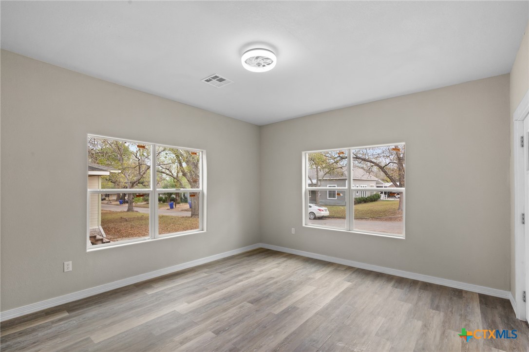 406 Hubbard Street Yoakum, TX 77995 - Photo 7 of 37 a view of an empty room with a window and wooden floor