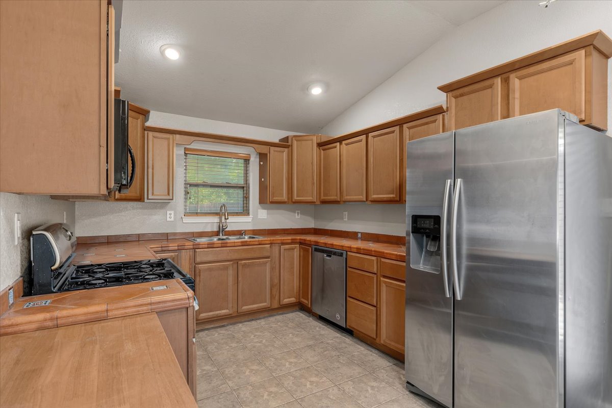 7604 Robalo Road Austin, TX 78757 - Photo 10 of 36 A functional kitchen features light wood cabinetry, essential appliances, and a tiled counter space.