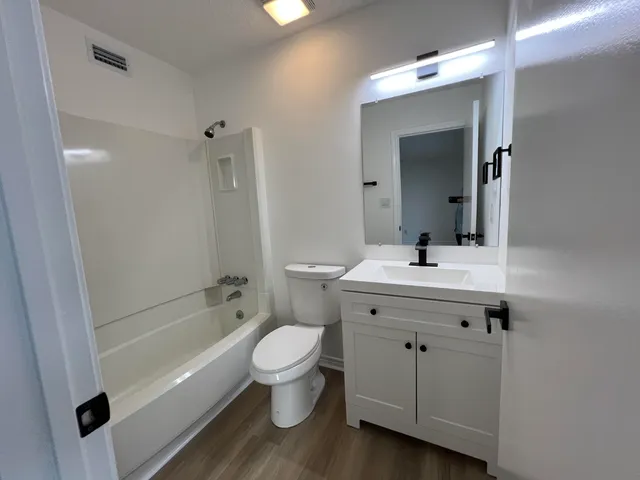 a white toilet sitting next to a white sink and vanity