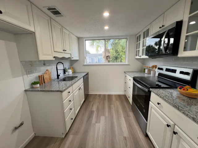 a kitchen with stainless steel appliances granite countertop a sink stove and cabinets