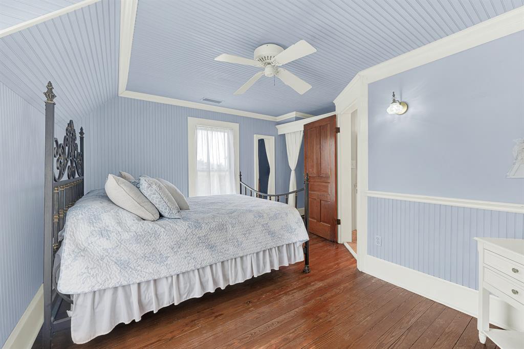 1425 Lone Star Road Celina, TX 75009 - Photo 18 of 40 Soft beadboard walls and ceilings, paired with restored original hardwood floors, create a bright, welcoming bedroom that feels both timeless and comfortable. Guests or family can settle in, open the windows, and enjoy the peaceful rhythm of country living.