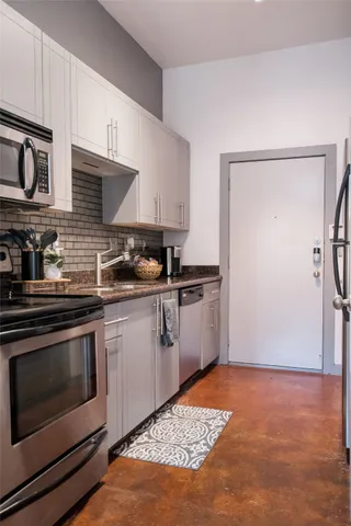 a kitchen with stainless steel appliances granite countertop a stove a sink and a refrigerator