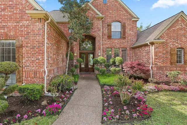 a view of a brick house with a flower garden