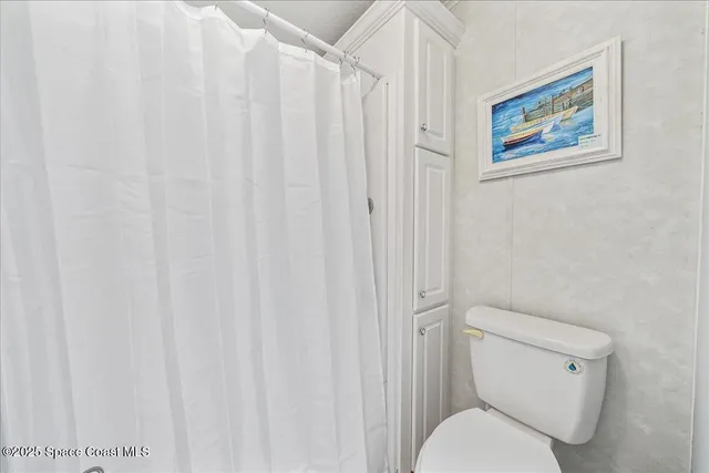 a white toilet sitting next to a shower curtain
