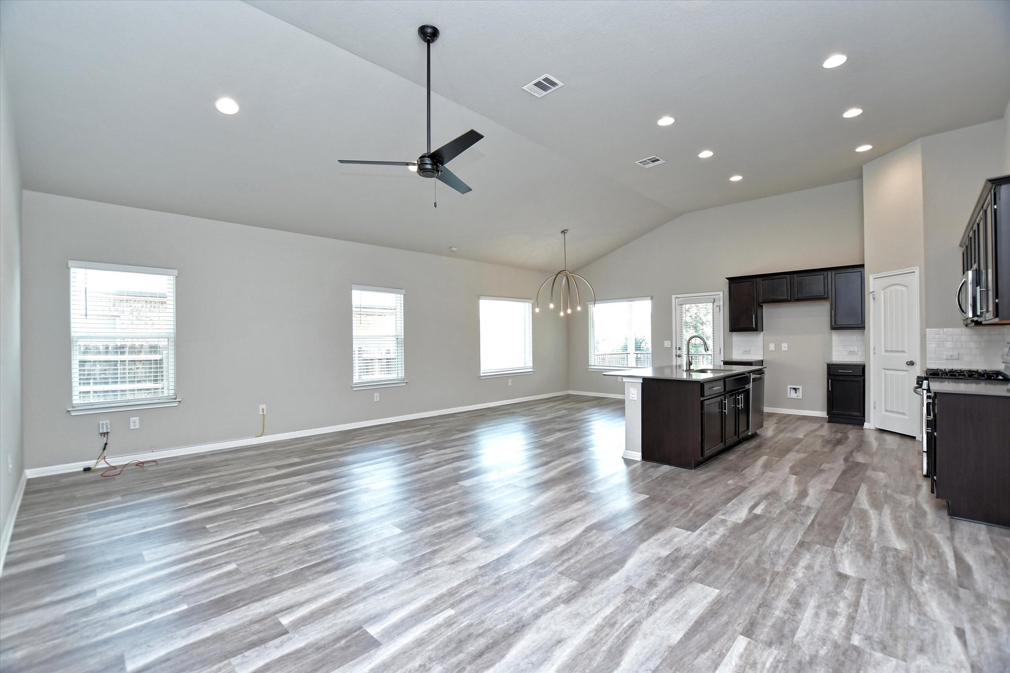 A spacious, open-concept living area with vaulted ceilings and ample natural light, seamlessly integrating kitchen and living spaces.