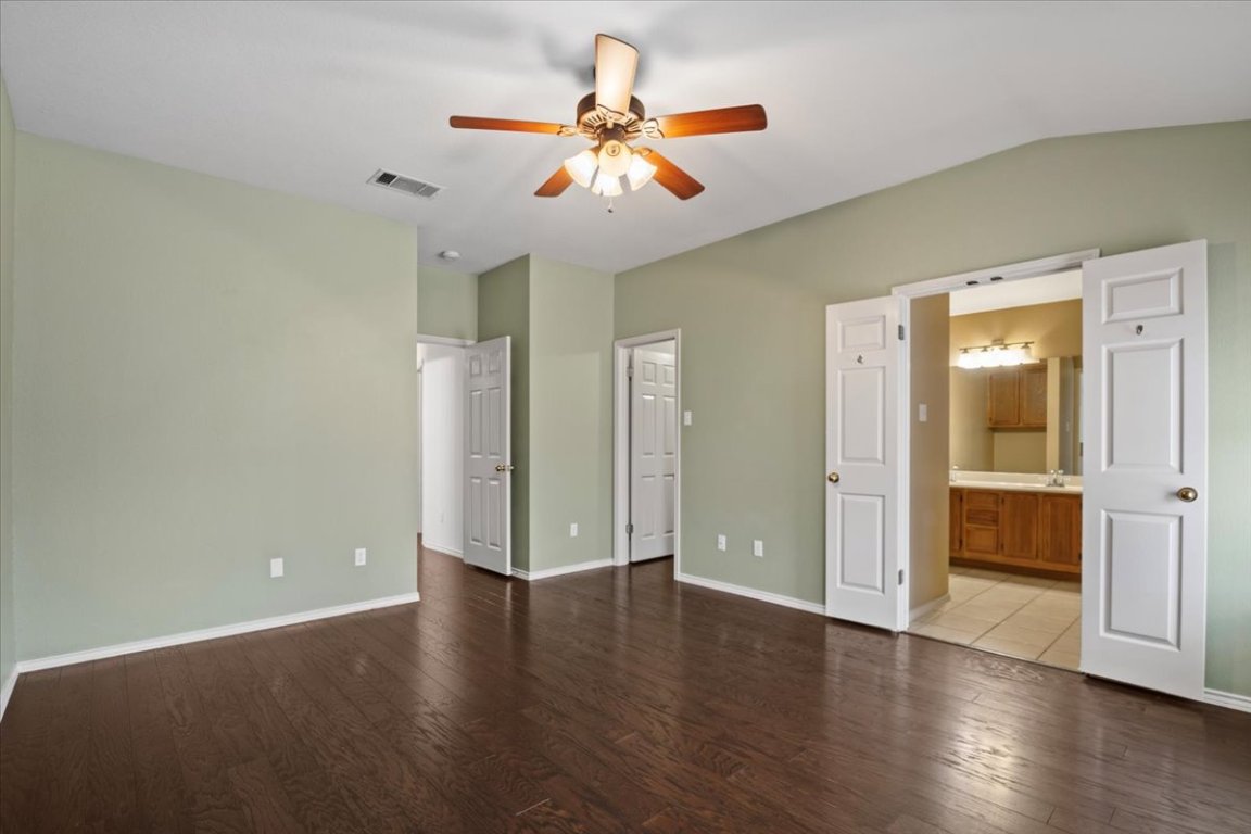 13438 Moscow Trail Austin, TX 78729 - Photo 22 of 40 Unfurnished bedroom with wood finished floors, lofted ceiling, and ensuite bathroom