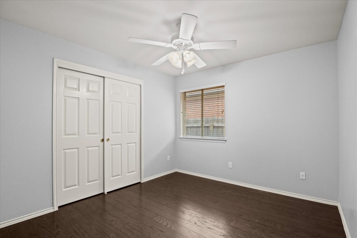 13438 Moscow Trail Austin, TX 78729 - Photo 27 of 40 Unfurnished bedroom featuring dark wood-style flooring, a closet, and a ceiling fan