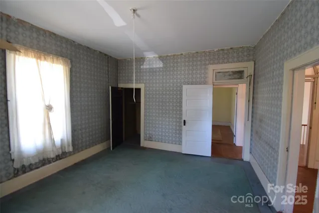 an empty room with wooden floor fireplace and staircase