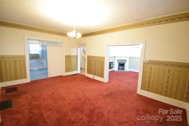 a view of an empty room with kitchen and a window