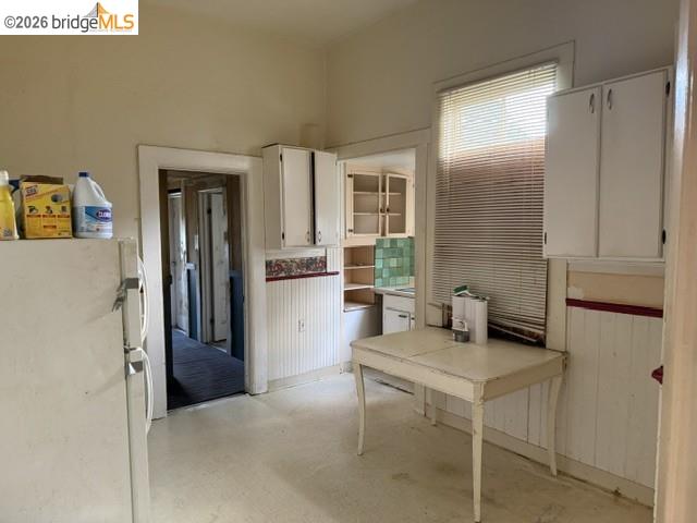 1717 9th Street Oakland, CA 94607 - Photo 3 of 4 Kitchen area featuring white cabinetry, a window with blinds, and beadboard paneling along the lower walls