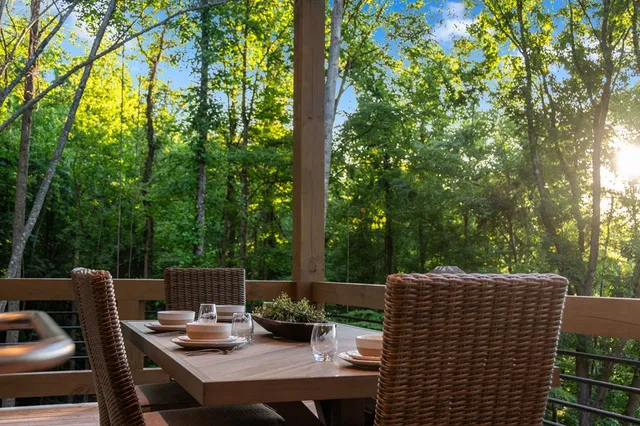 a backyard of a house with table and chairs potted plants and large tree