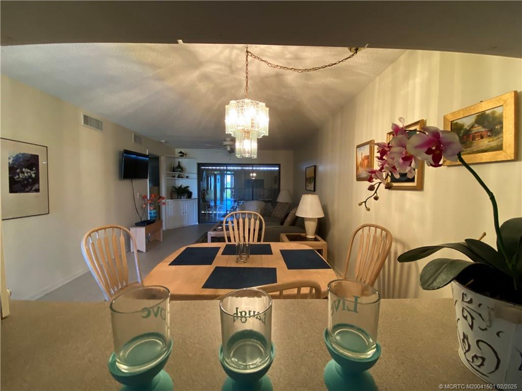 4620 Northeast Sandpebble Trace, Unit 405 Stuart, FL 34996 - Photo 14 of 26 a dining room with furniture and chandelier kitchen view