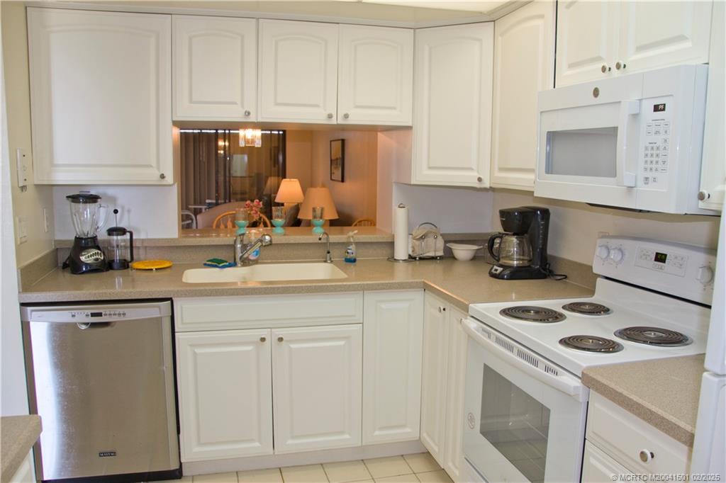 4620 Northeast Sandpebble Trace, Unit 405 Stuart, FL 34996 - Photo 15 of 26 a kitchen with white cabinets and white appliances
