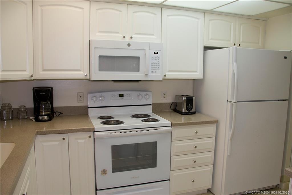 4620 Northeast Sandpebble Trace, Unit 405 Stuart, FL 34996 - Photo 16 of 26 a kitchen with white cabinets and white appliances