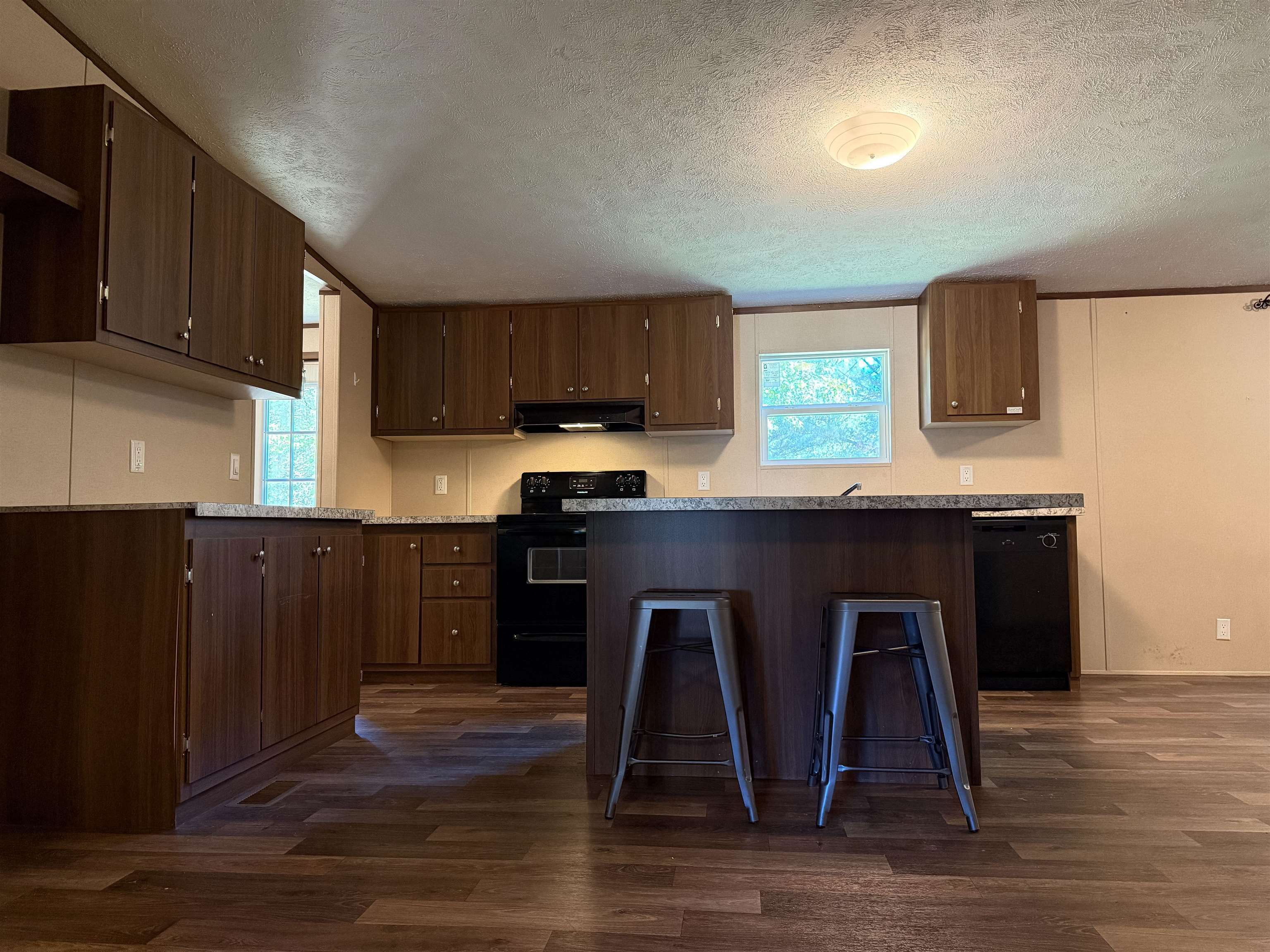 279 Travis Road Brewton, AL 36426 - Photo 6 of 17 Kitchen with light countertops, black appliances, a textured ceiling, dark wood-style flooring, and dark brown cabinets