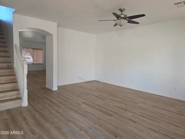 a view of empty room with wooden floor and ceiling fan