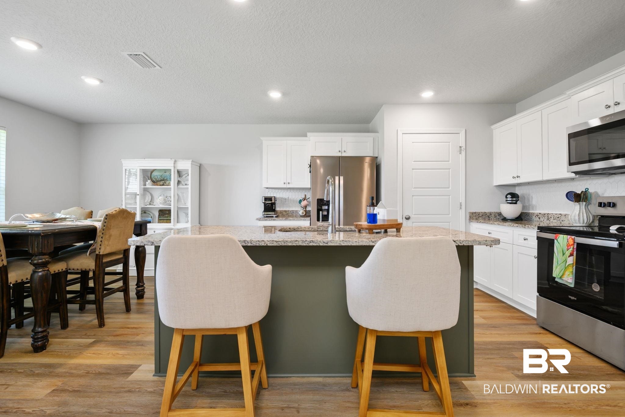 8021 Valor Rdg Way North Mobile, AL 36619 - Photo 24 of 34 Spacious kitchen featuring an island with a light-toned countertop, stainless steel appliances, white cabinetry, and wood-finish flooring