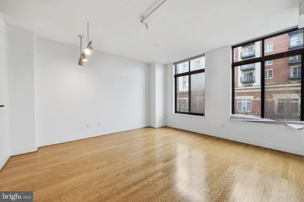 a view of an empty room with a window and kitchen view