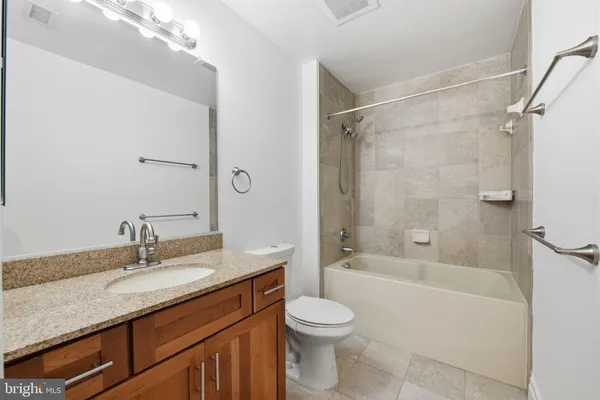 a bathroom with a granite countertop sink a toilet and shower