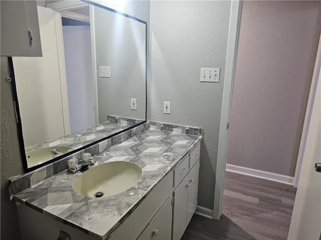 a bathroom with a granite countertop bathtub shower sink vanity and toilet