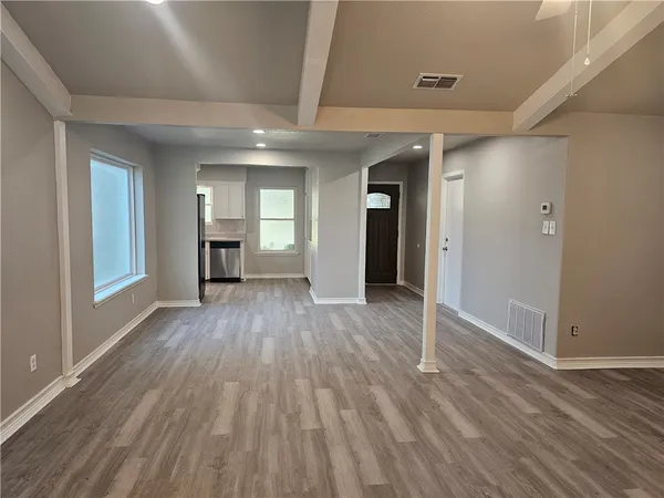 an empty room with wooden floor and windows
