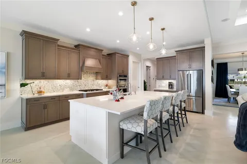 a kitchen with stainless steel appliances kitchen island granite countertop a table chairs sink and cabinets