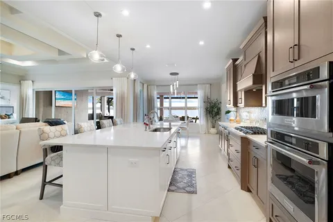 a large white kitchen with lots of counter space a sink appliances and cabinets
