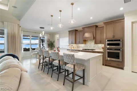 a kitchen with stainless steel appliances kitchen island granite countertop a stove a sink a refrigerator and chairs