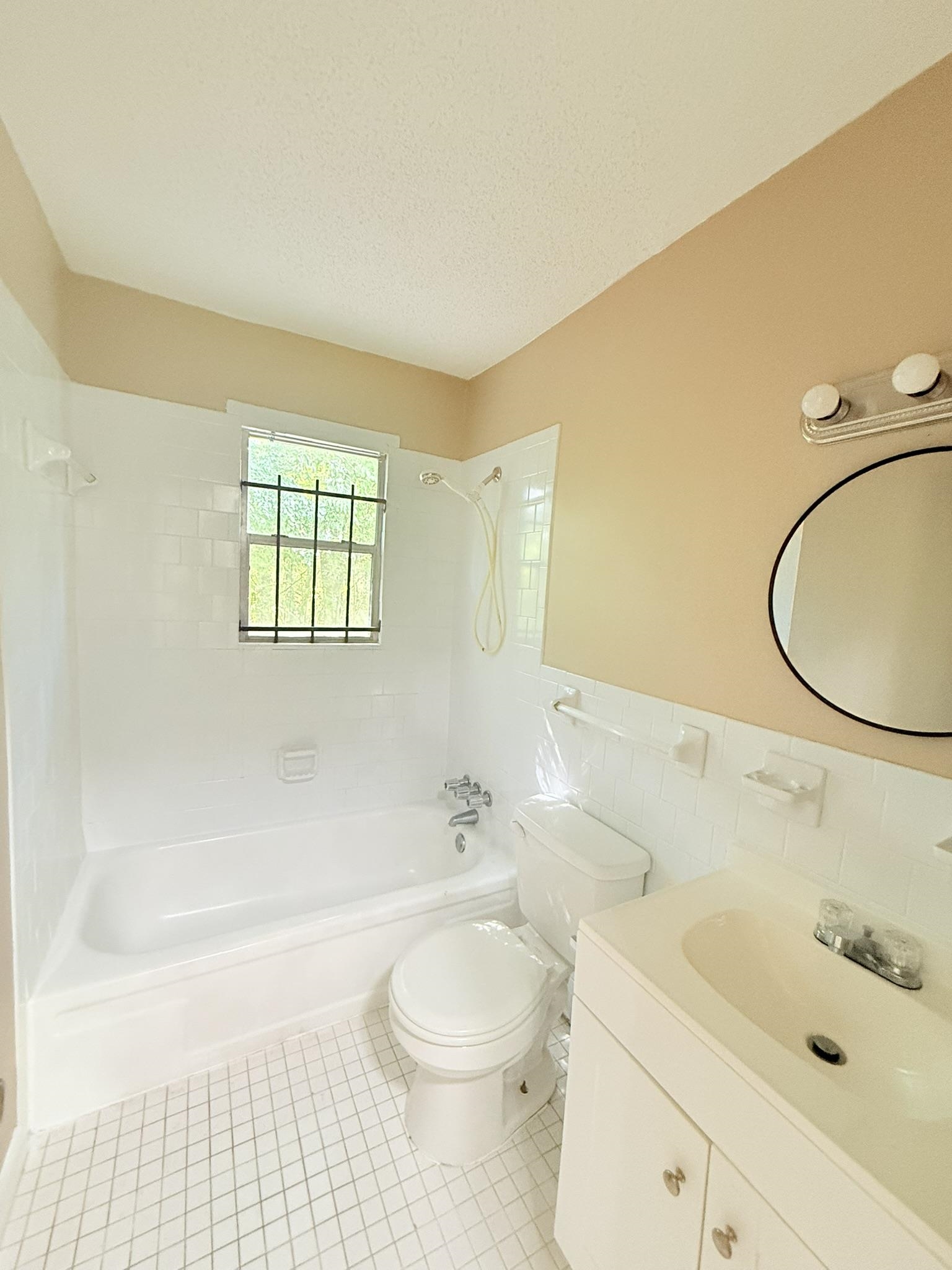 931 Calvin Road Memphis, TN 38109 - Photo 7 of 15 Full bath featuring shower / bathtub combination, vanity, light tile patterned floors, tile walls, and a textured ceiling