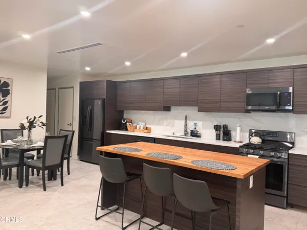 a kitchen with stainless steel appliances granite countertop a table chairs sink and cabinets