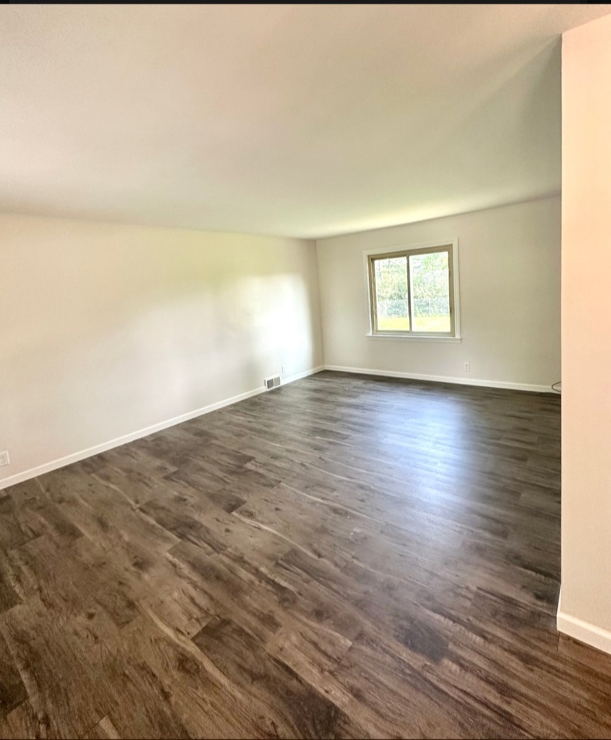 906 West Walnut Street Kankakee, IL 60901 - Photo 2 of 14 an empty room with wooden floor and windows