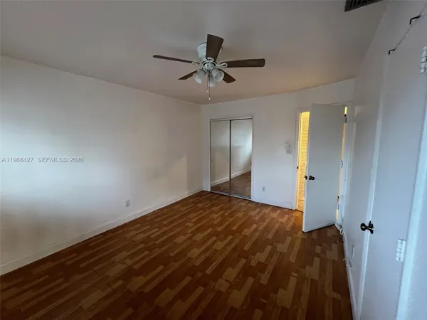 an empty room with wooden floor closet and windows