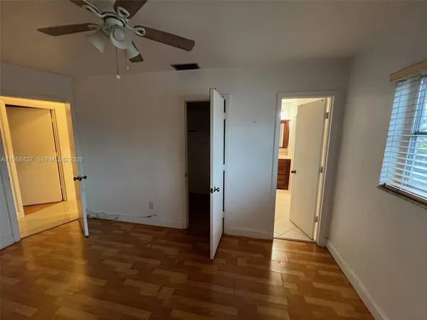 an empty room with wooden floor ceiling fan