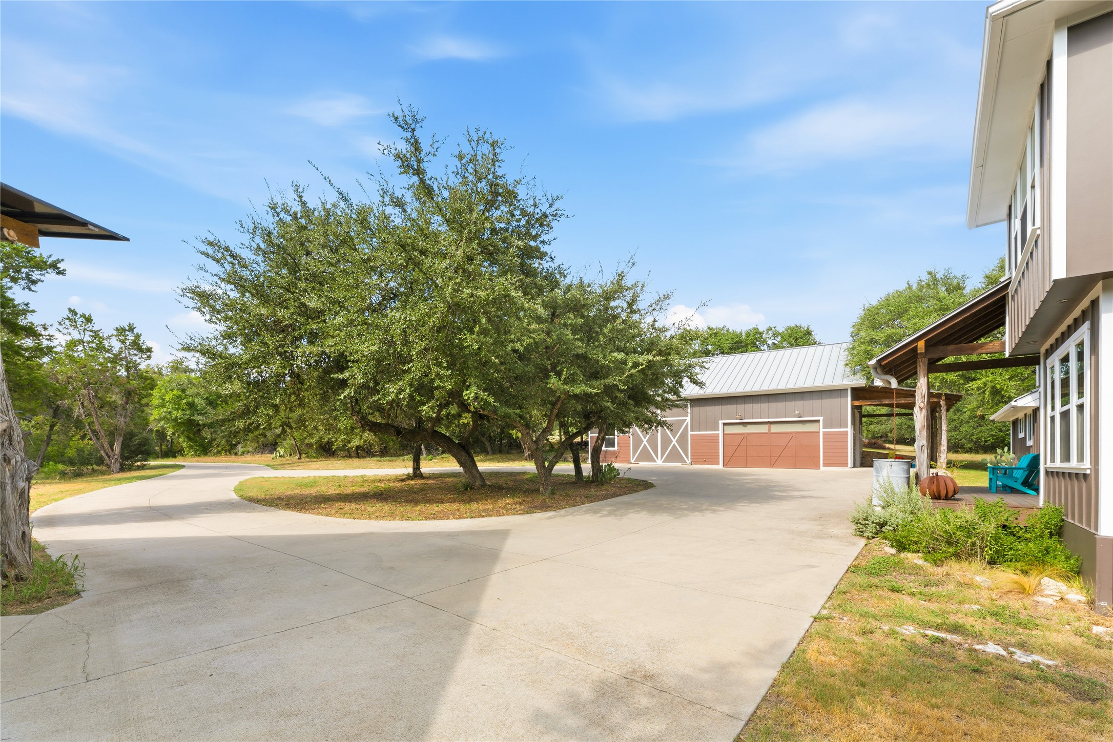 12901 Wire Road Leander, TX 78641 - Photo 31 of 40 A sweeping concrete driveway leads to a detached garage among mature trees.