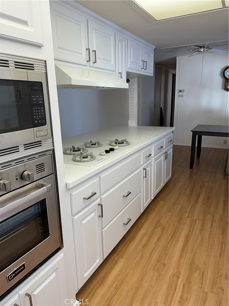 33853 Plowshare Road Wildomar, CA 92595 - Photo 22 of 25 a kitchen with granite countertop cabinets stainless steel appliances and wooden floor