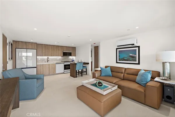 a living room with furniture a rug kitchen view and a window