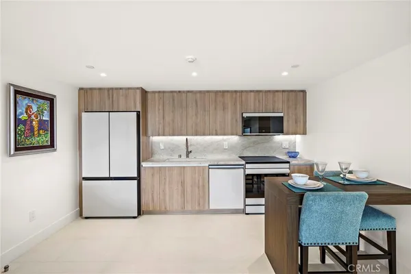 a kitchen with stainless steel appliances granite countertop a refrigerator a stove a sink a microwave a dining table and chairs
