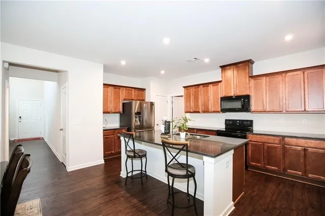 a kitchen with stainless steel appliances a sink a stove a refrigerator cabinets and a dining table